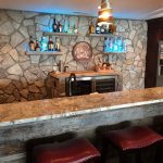 built in a bar with lighted liquor shelves of stone, granite and barnwood
